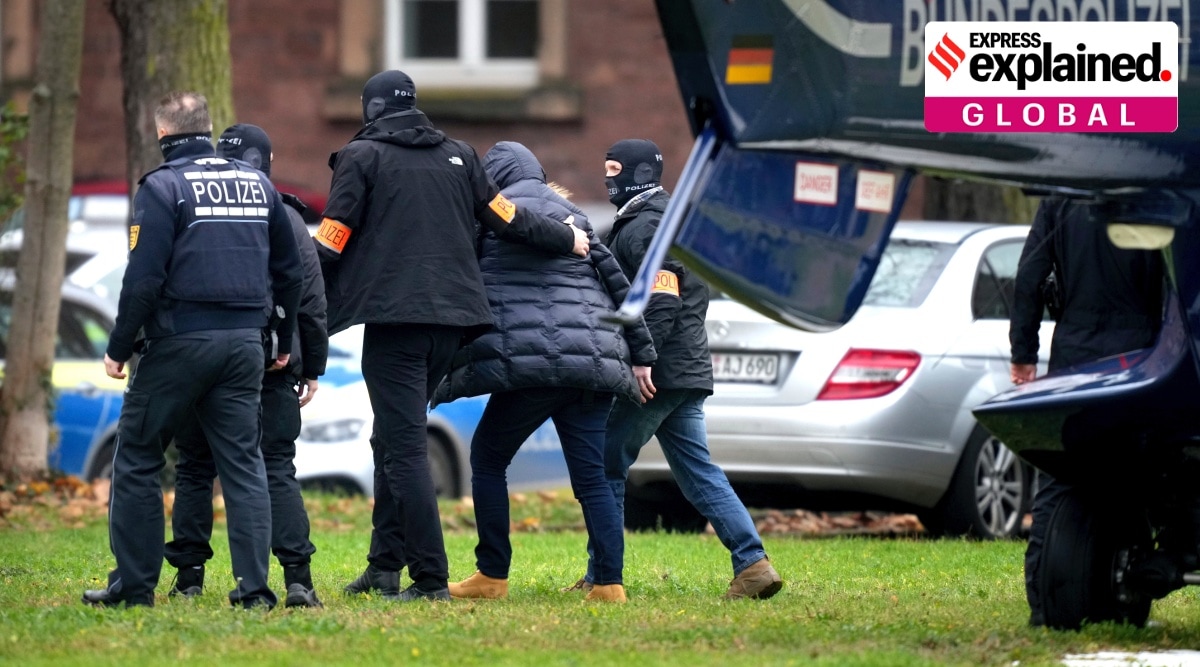 An suspect, second right, is escorted from a police helicopter by police officers after the arrival in Karlsruhe, Germany, Wednesday, Dec. 7, 2022. Thousands of police officers carried out raids across much of Germany on Wednesday against suspected far-right extremists who allegedly sought to overthrow the government in an armed coup. Officials said 25 people were detained. (AP Photo/Michael Probst)