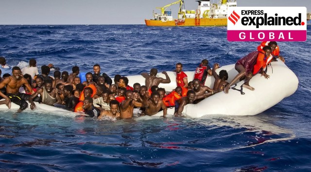 African refugees desperately hanging on to a sinking boat as a rescue vessel approaches
