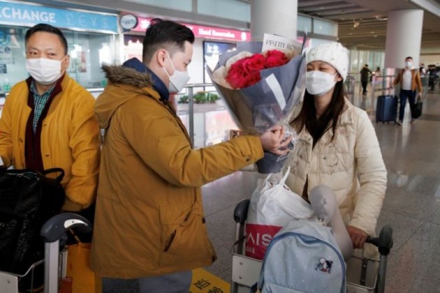 In this photo, a man hands flowers to a woman after she came through the international arrivals gate at Beijing Capital International Airport as China lifted the coronavirus quarantine. (Reuters)