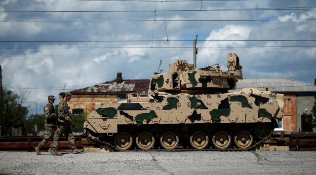 U.S. servicemen walk past a Bradley infantry fighting vehicle as they arrive for the joint U.S.-Georgian exercise Noble Partner 2016 in Vaziani