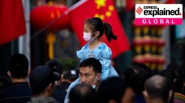 A girl wearing a face mask rides on a man's shoulders as they walk along a tourist shopping street in Beijing on Oct. 7, 2022.