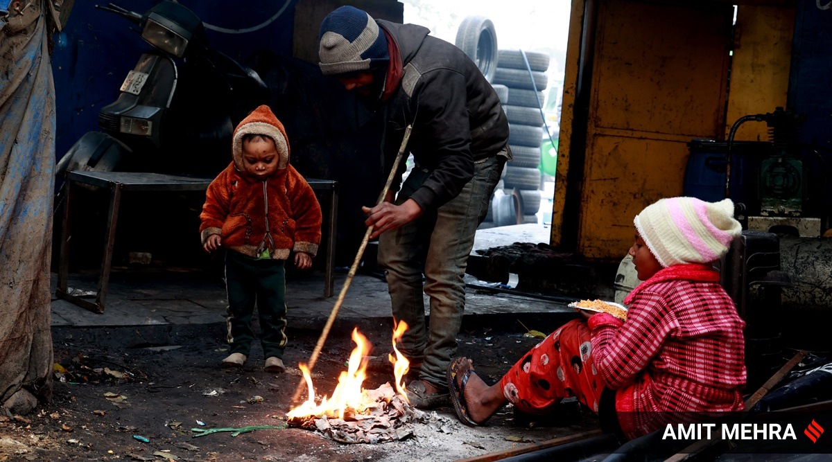 People sit in front of a fire on a cold and foggy morning in New Delhi. (Express Photo by Amit Mehra)