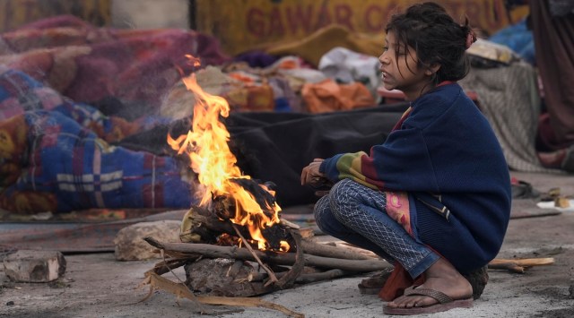 A child sits near a bonfire to warm herself on a cold winter morning, in New Delhi, January 10, 2023. (PTI)