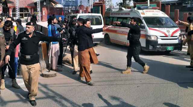 Police officers clear the way for ambulances leaving after carrying wounding people from bomb explosion site, at the main entry gate of police offices, in Peshawar, Pakistan, Monday, Jan. 30, 2023. (AP Photo/Muhammad Sajjad)