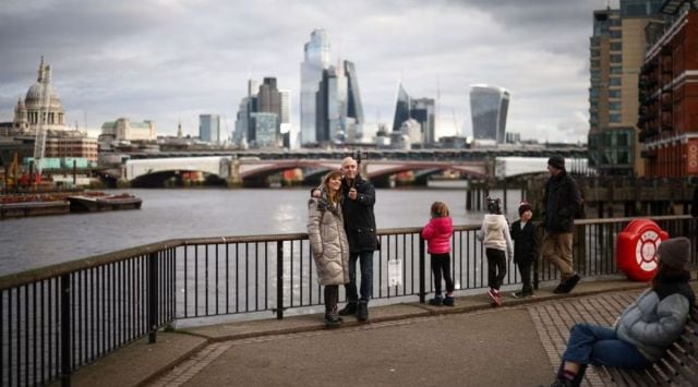 People take a selfie next to the bank of the River Thames, with the City of London financial district in the background, in London, Britain. (REUTERS)