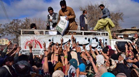 People jostle to buy subsidized sacks of wheat-flour from a sale point in Quetta, Pakistan, January 12, 2023. People are suffering from recent price hike in wheat-flour in Pakistan. (AP/PTI)