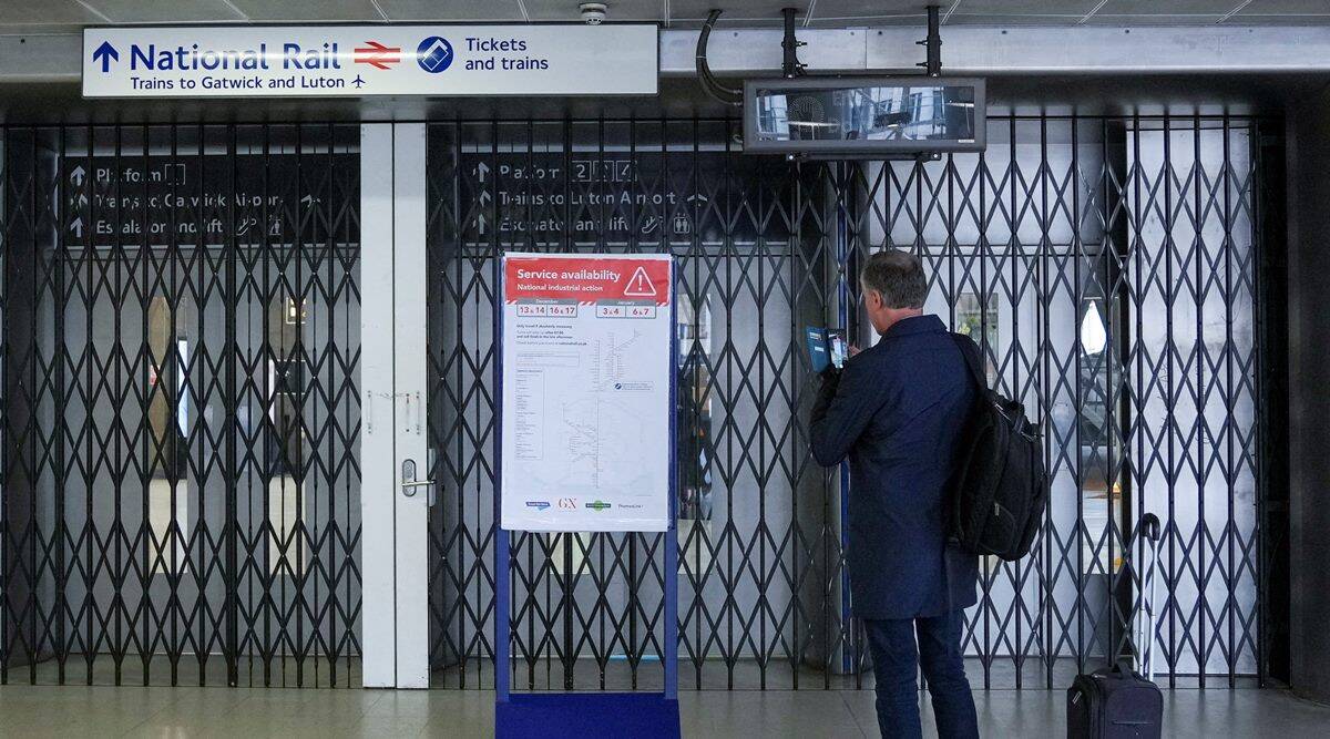 A traveller stands before a closed gate as rail workers strike over pay and terms at Blackfriars station in London. (Reuters)