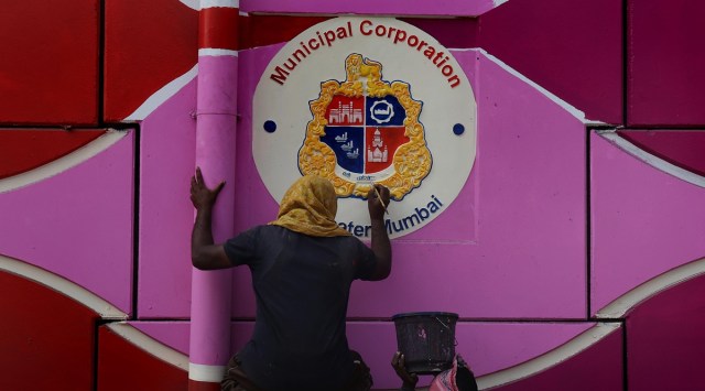 The BMC logo being painted on the wall of Mankhurd flyover on Friday. (Express Photo by Amit Chakravarty)