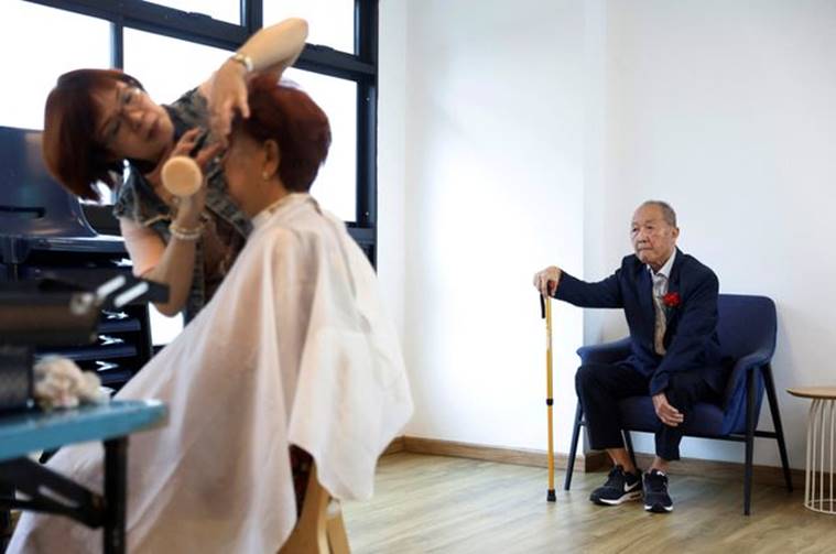 Tan Chee Hwa waits as his wife Yong Mok Lan gets her make up done before a ceremony to renew their marriage vows on Valentine's Day in Singapore