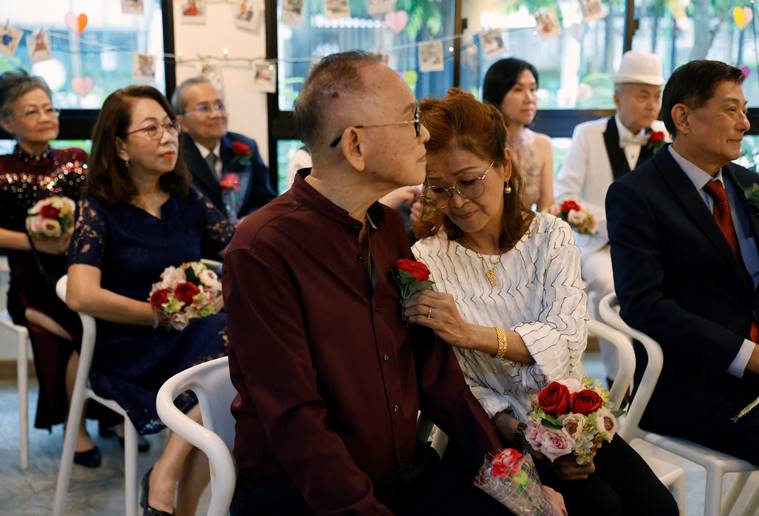 Agnes Cheong adjusts the flower on her husband Chan Chuck Wai's shirt as they attend a ceremony to renew their marriage vows on Valentine's Day in Singapore