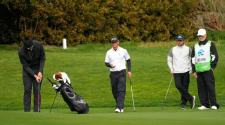 Beau Hossler, left, putts on the 13th green of the Pebble Beach Golf Links as Max McGreevy, center, and Lukas Nelson, second from right, look on during the second round of the AT&T Pebble Beach Pro-Am golf tournament in Pebble Beach, Calif., Friday, Feb. 3, 2023. A caddie for one of the amateurs in the group collapsed on the 11th fairway and was rushed to the hospital. (AP Photo/Eric Risberg)