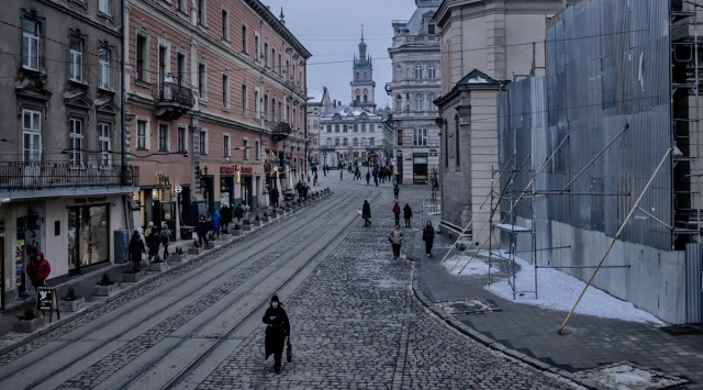 People move through Katedralna Square, where the Archcathedral Basilica of the Assumption of the Blessed Virgin Mary is boarded up to protect from possible shelling, in Lviv, Ukraine, Feb. 11, 2023. (Maciek Nabrdalik/The New York Times)
