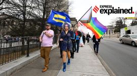 Trans rights activists carrying rainbow, equality flags march past the state capitol