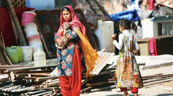 A woman stands with a cat amid rubble in Mehrauli, Delhi.