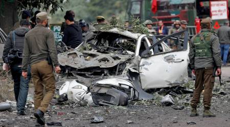 Indian security force personnel stand guard next to a damaged vehicle after a bomb blast in Narwal area of Jammu. (Reuters)
