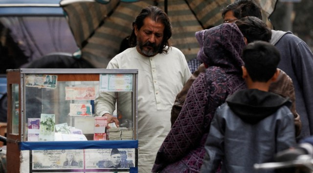 A currency broker stands near his booth, which is decorated with pictures of currency notes, while dealing with customers, along a road in Karachi, Pakistan January 27, 2023. (Reuters)
