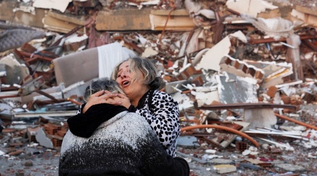 A woman reacts while embracing another person, near rubble following an earthquake in Hatay, Turkey, February 7, 2023. (Reuters)