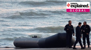 French policemen stand beside a dinghy lying on the beach after migrants tried to reach Britain