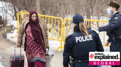 RCMP officers approach a woman as enters Canada via Roxham road on the Canada/US border on Saturday, March 25, 2023.