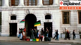 An anti-apartheid protest is seen in London, UK, at South Africa House in 1989 with people waving flags with yellow, green, red and black stripes.