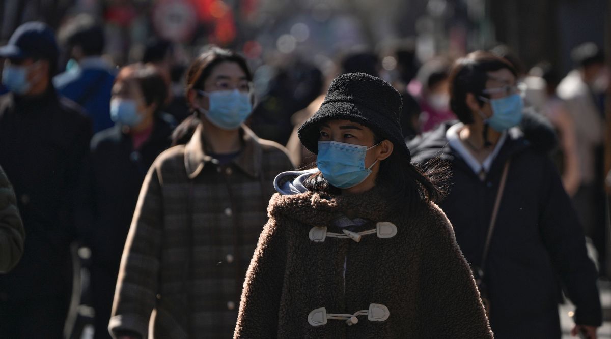 People wearing face masks tour at a tourist shopping street in Beijing. (AP)