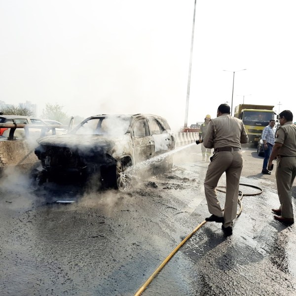 Police and fire department officials put out the fire from the Toyota Fortuner car on the Noida-Greater Noida Expressway. (Express photo)