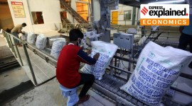 Workers in a factory packaging sugar in sacks.