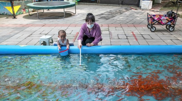 A woman with a child at a park in Beijing, on June 12, 2022. (Gilles Sabrié/The New York Times)