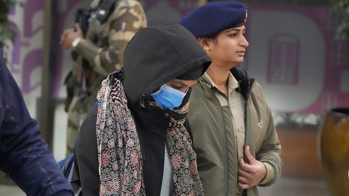 Police officials escort a woman who was deported from the US, at Amritsar airport on Wednesday