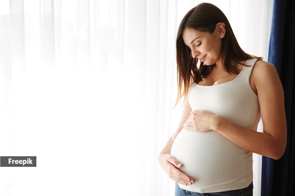 Premium Photo  A pregnant woman stands against a white wall and