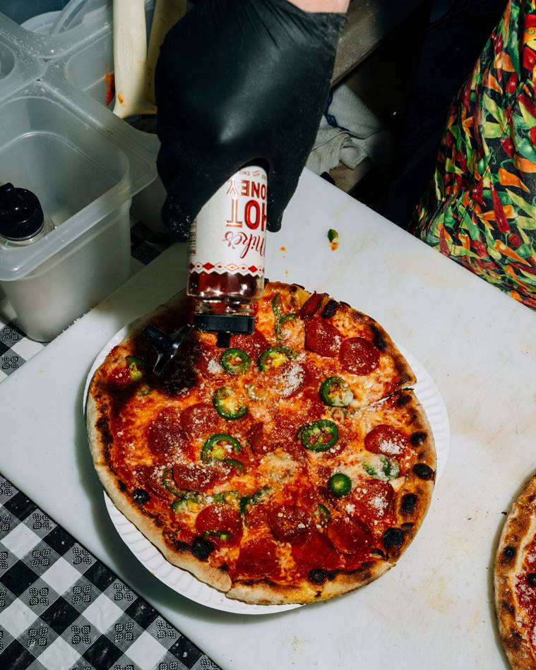 Hot honey is drizzled on a Jabroni Pepperoni pizza from the Happy Bull pop-up at Fifth Hammer Brewing in Queens, April 18, 2023. (DeSean McClinton-Holland/The New York Times)