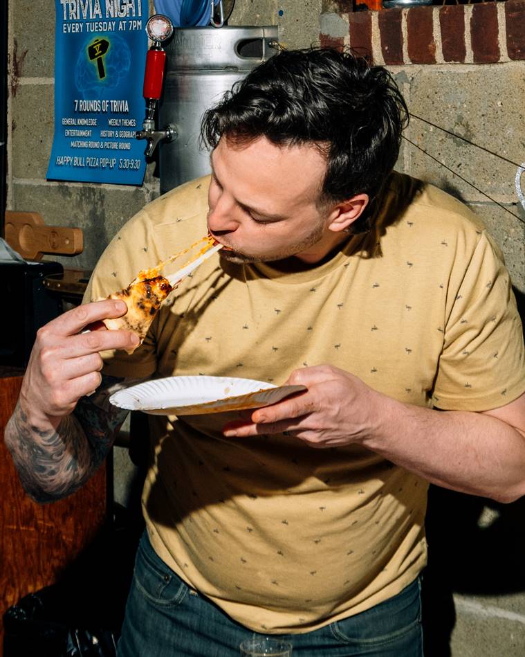 Ian McHugh celebrates his birthday with pizza from the Happy Bull pop-up at Fifth Hammer Brewing in Queens, April 18, 2023. (DeSean McClinton-Holland/The New York Times)