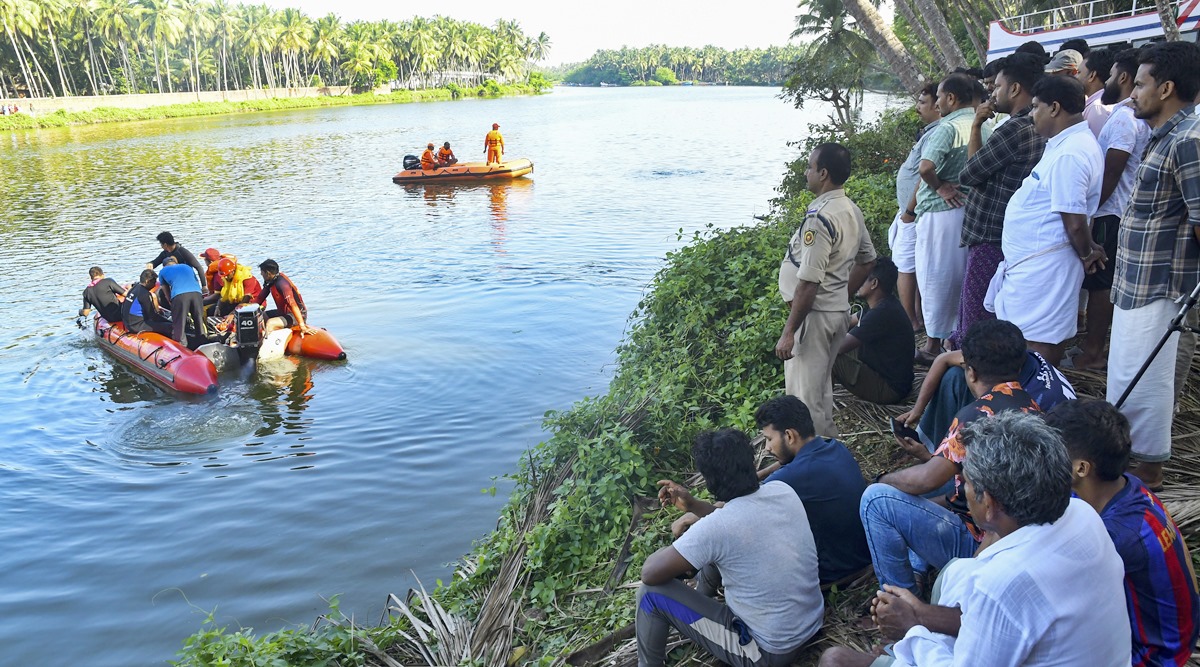 people watch rescuers on a boat search a river after a tourist boat capsized Sunday night in Malappuram, Kerala, May 8, 2023. (AP)