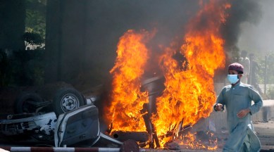 A man runs past a burning car set on fire by angry supporters of Pakistan's former Prime Minister Imran Khan during a protest against the arrest of their leader, in Peshawar, Pakistan, May 10, 2023. (AP)