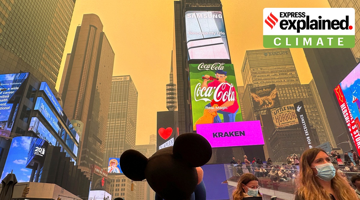 People walk in Times Square as Manhattan is shrouded in haze and smoke which drifted south from wildfires in Canada.