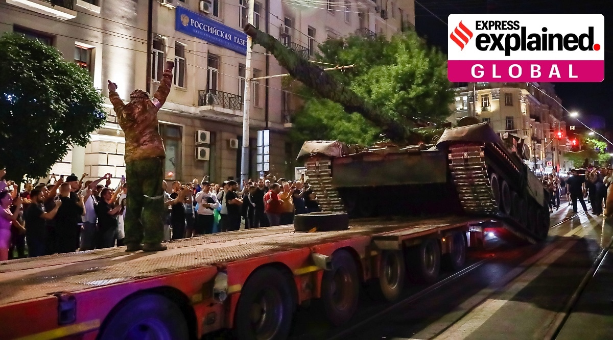 Members of the Wagner Group military company load their tank onto a truck on a street in Rostov-on-Don.