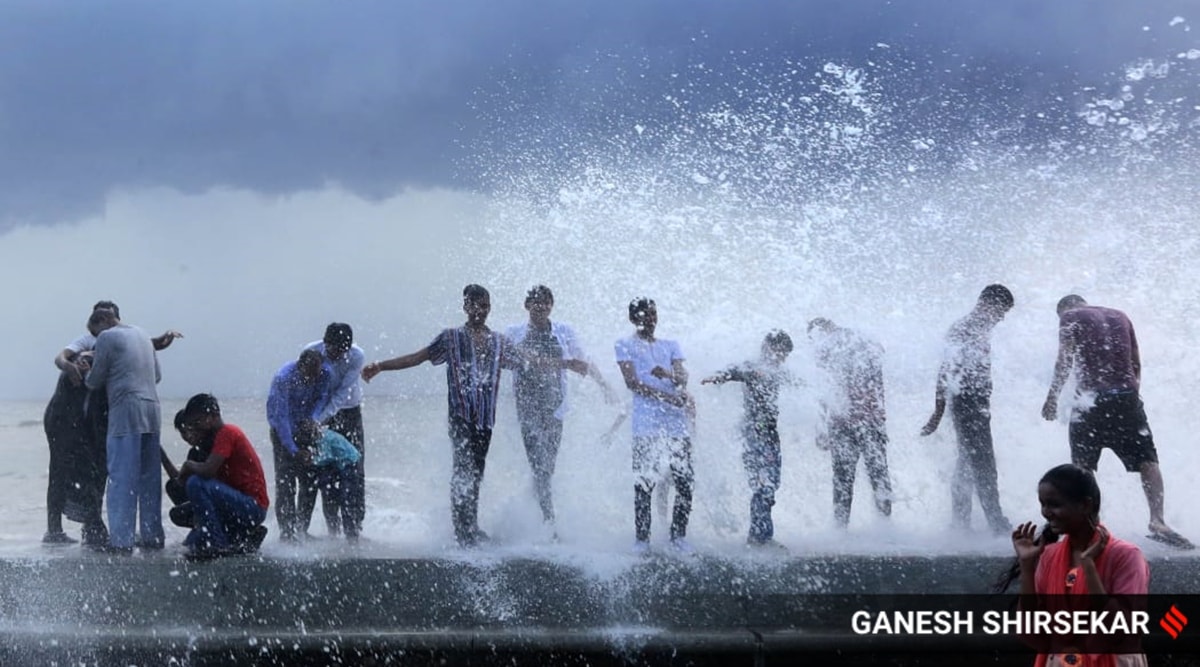 People enjoy as rain and tidal waves hit Mumbai coast on Sunday. (Express photo by Ganesh Shirsekar)