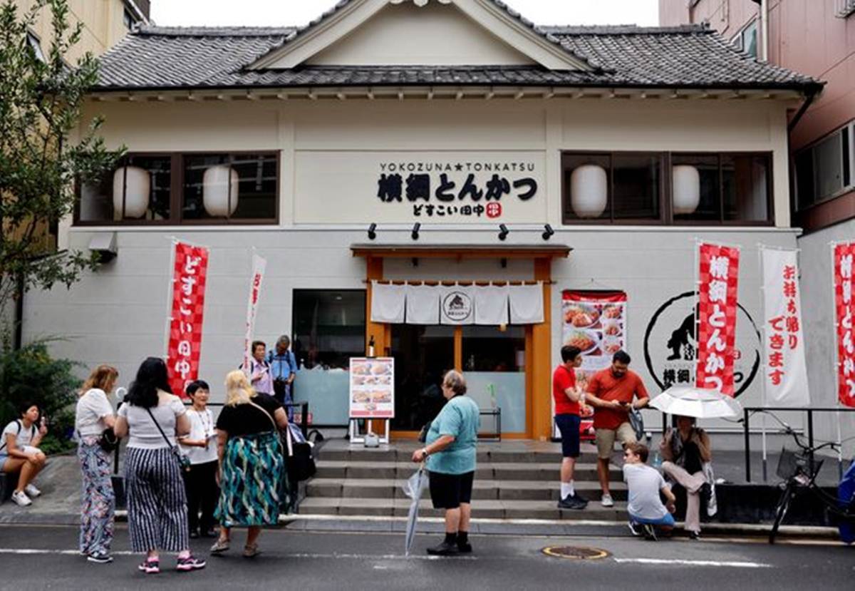 Tourists from abroad wait for Yokozuna Tonkatsu Dosukoi Tanaka, a sumo wrestling themed restaurant to open, in Tokyo