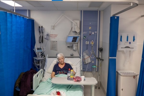 Marianne Patten waits in an emergency room bed for a hospital room to open at Queen's Hospital, where waiting times have improved but more than half of patients with serious illnesses or injuries still wait more than four hours to be treated, in Romford, England, March 20, 2023 ( Andrew Testa/The New York Times)