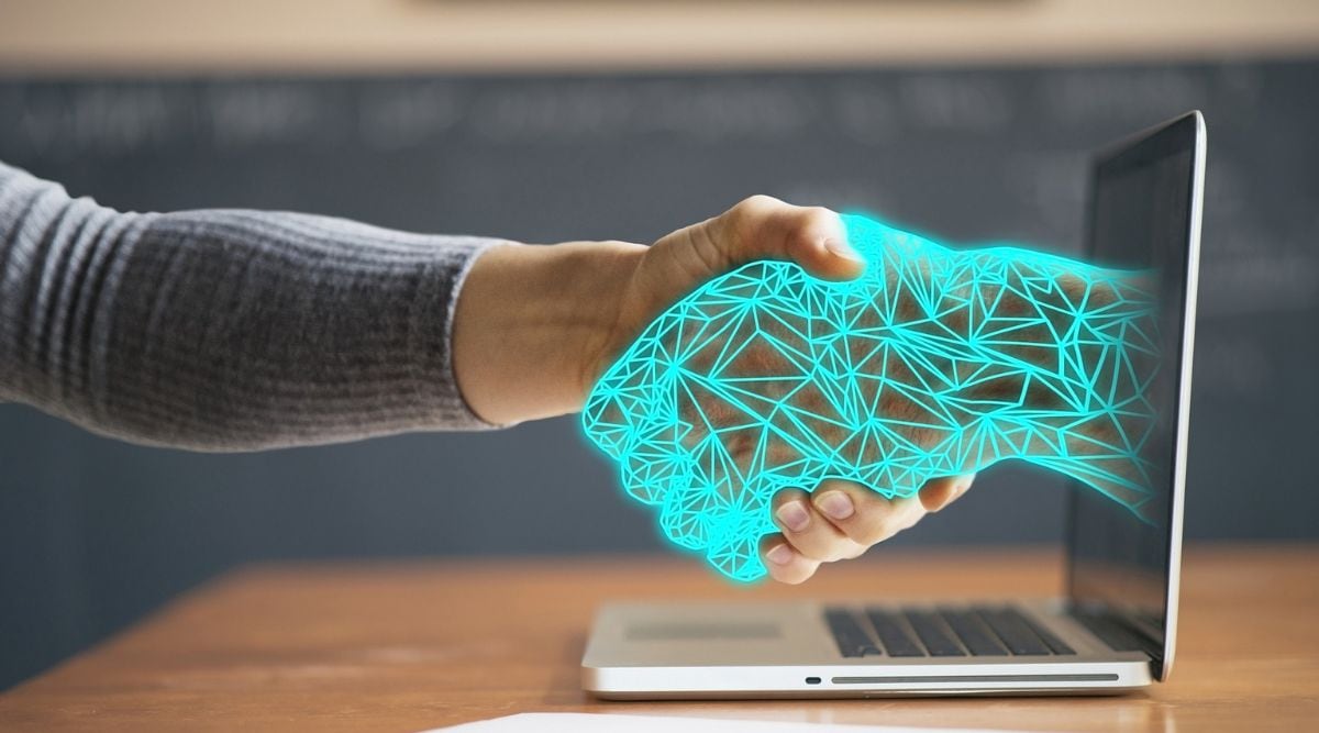 handshake between a human and a virtual hand poking out of a laptop