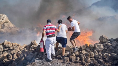 Local residents try to extinguish a fire, near the seaside resort of Lindos, on the Aegean Sea island of Rhodes, southeastern Greece