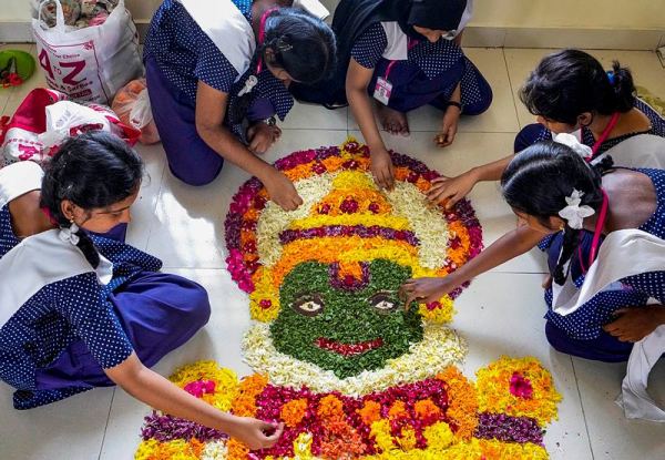 Students participate in a 'pookalam' making competion. Picture: PTI Photo/R Senthil Kumar