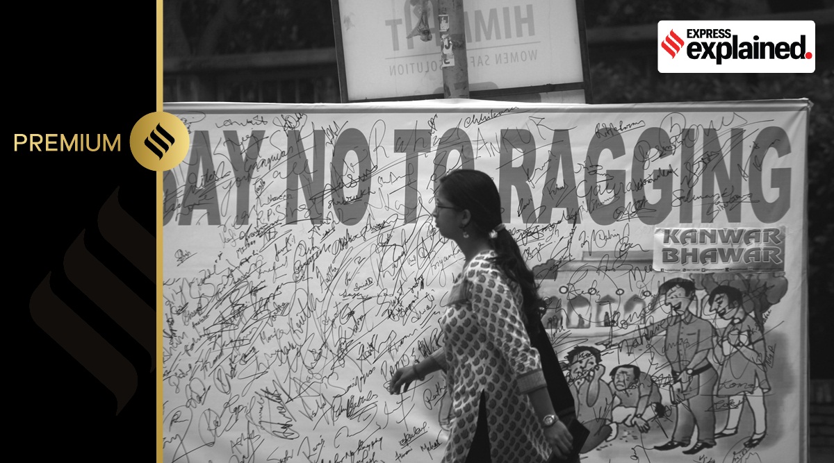A student walks past a banner that says 'Sat No to Ragging'.