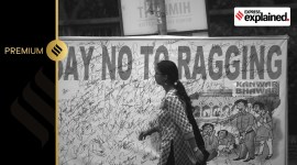 A student walks past a banner that says 'Sat No to Ragging'.