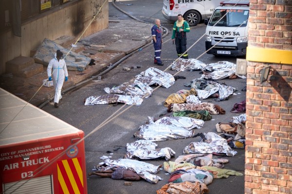 Medics stand by the covered bodies of victims of a deadly blaze in downtown Johannesburg, Aug. 31, 2023. (AP Photo)