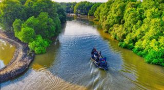 A boat traversing a waterway surrounded by mangroves.