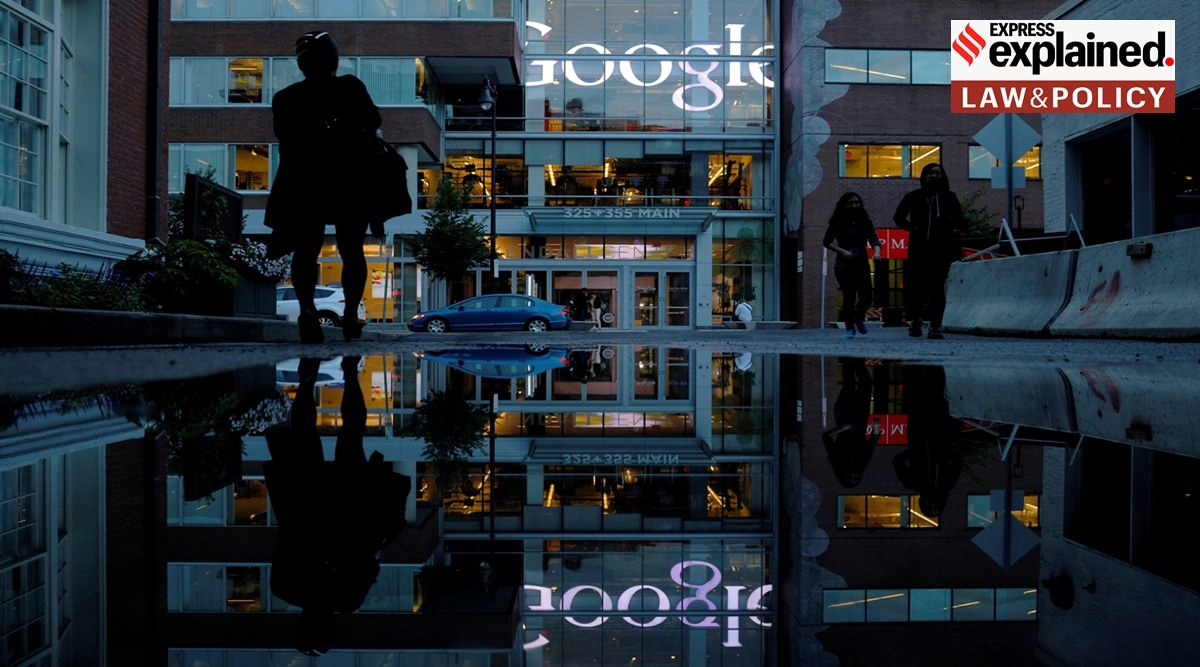 The Google sign is reflected in a rain puddle outside their offices in Cambridge