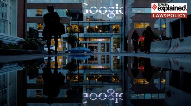 The Google sign is reflected in a rain puddle outside their offices in Cambridge