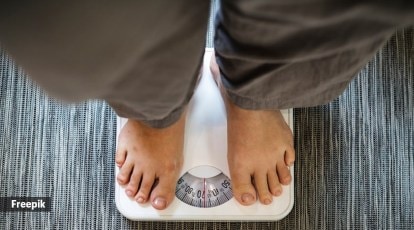 Fat man measuring his weight on a scale. top view.bare feet of an overweight  man