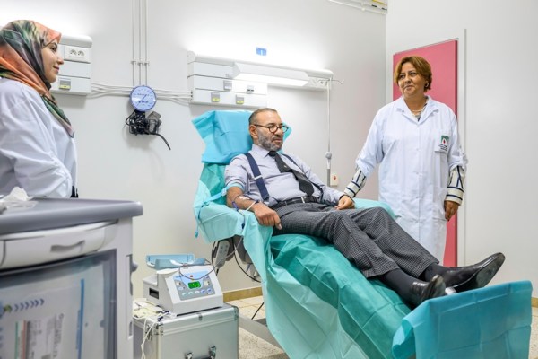 In this photo released by the Royal Palace, Morocco's King Mohammed VI, center, makes a blood donation for the needs of victims of the September 8 earthquake at the "Mohammed VI" University Hospital Center in Marrakech, Morocco. Tuesday 12, 2023. (Moroccan Royal Palace via AP)